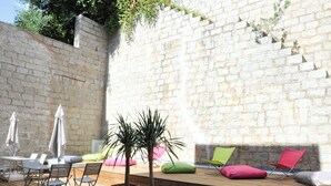 Un patio al aire libre con muro de piedra, terraza de madera y zona de estar.