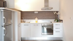Cocina moderna con horno empotrado, campana extractora de acero inoxidable y refrigerador de doble puerta.