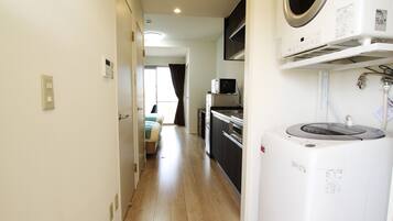 A compact kitchen with a microwave, oven, and washing machine.