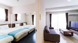 Une chambre d’hôtel avec deux lits, un canapé, une télévision et un plancher en bois.