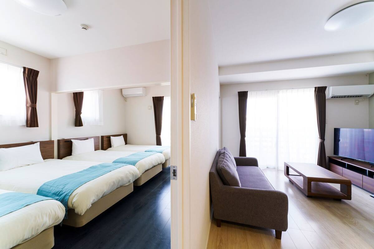 Une chambre d’hôtel avec deux lits, un canapé, une télévision et un plancher en bois.