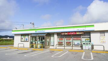 A FamilyMart store with a clear entrance, parking lot, and a sign indicating a 820 yen price for a product.