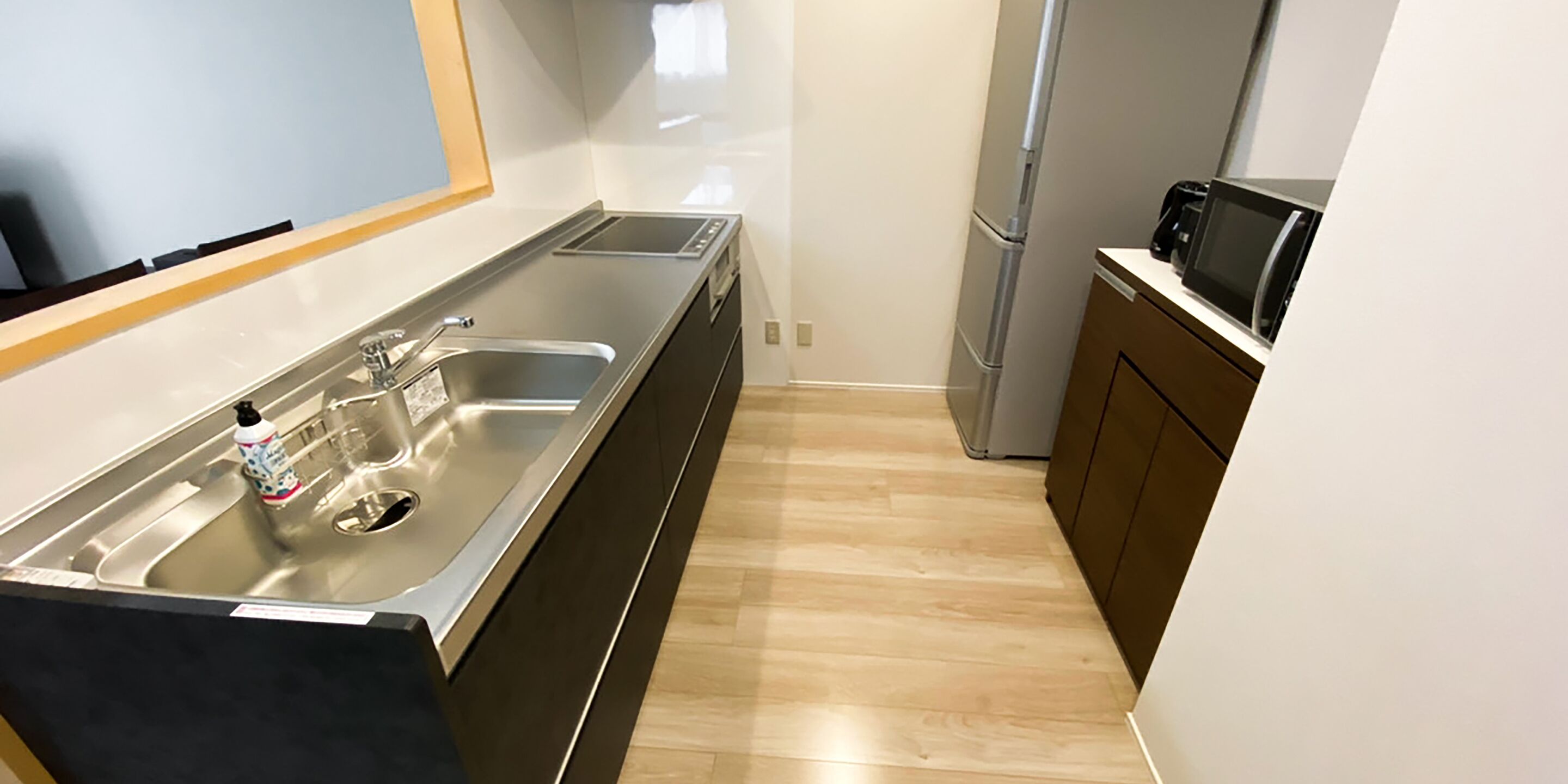 A modern kitchen with a stainless steel sink, a microwave, and a refrigerator.