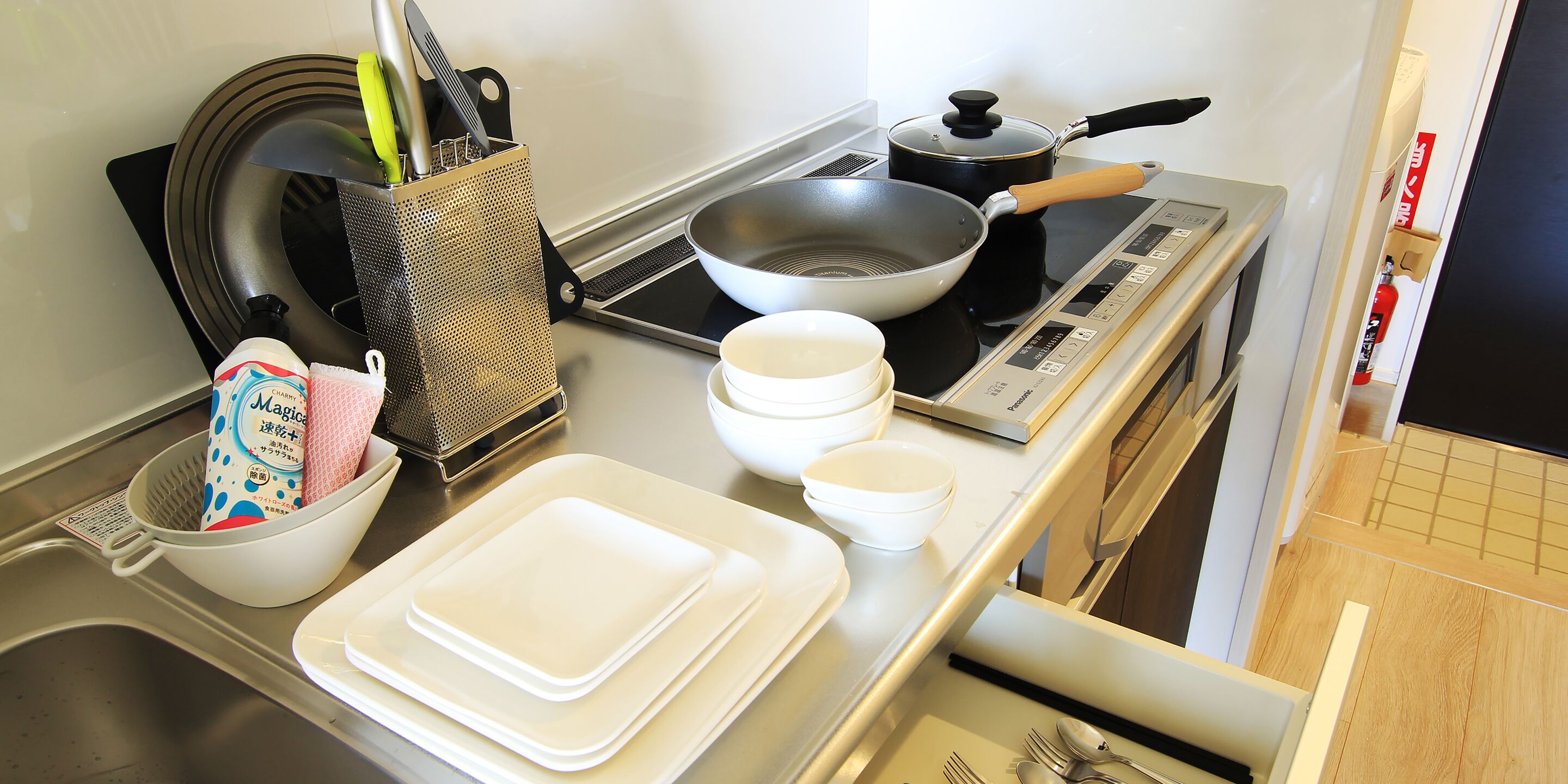 A kitchen with a stove, pots, pans, and various kitchen utensils.