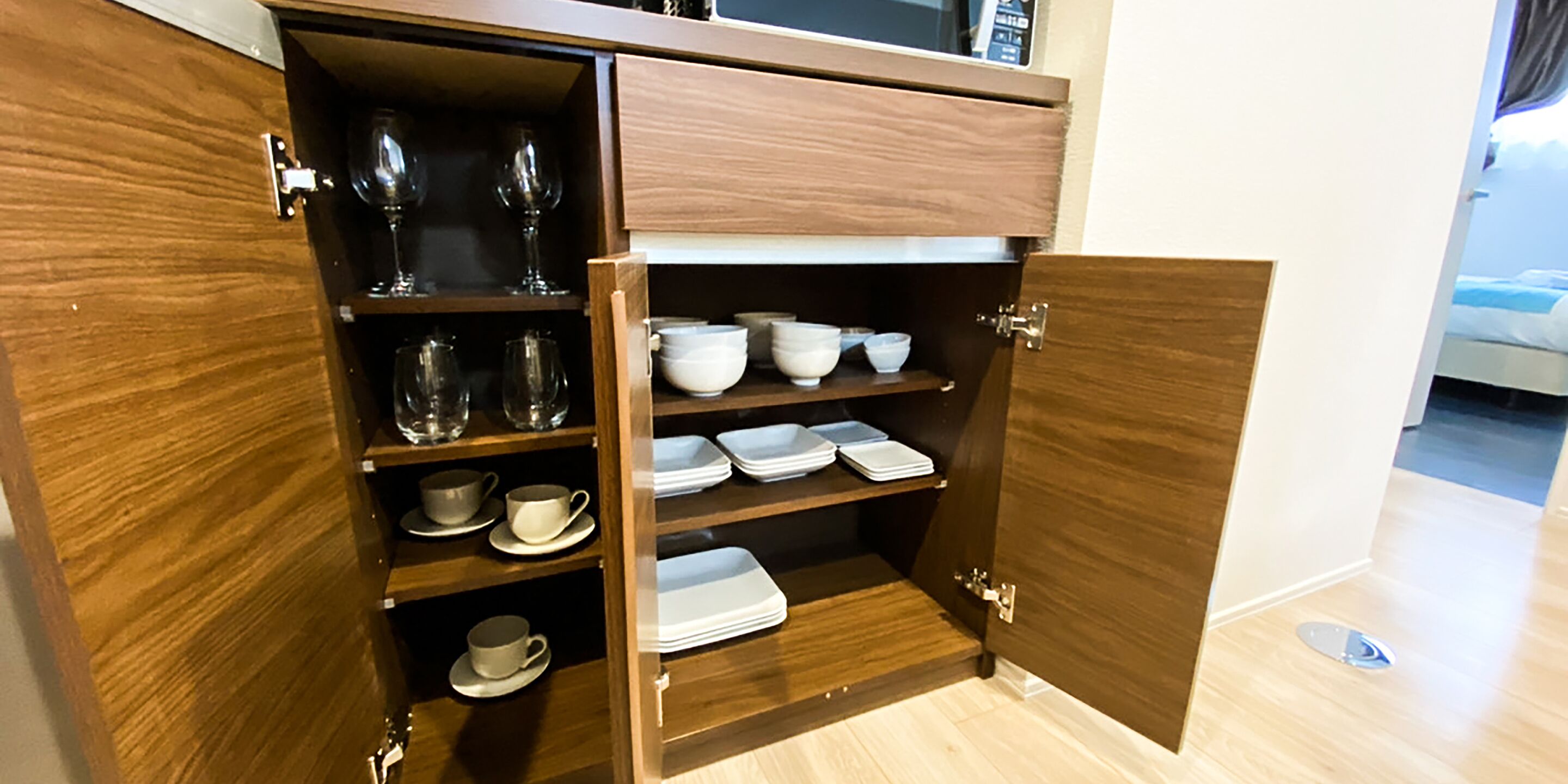 A wooden cabinet with multiple shelves containing various dishes and glassware.