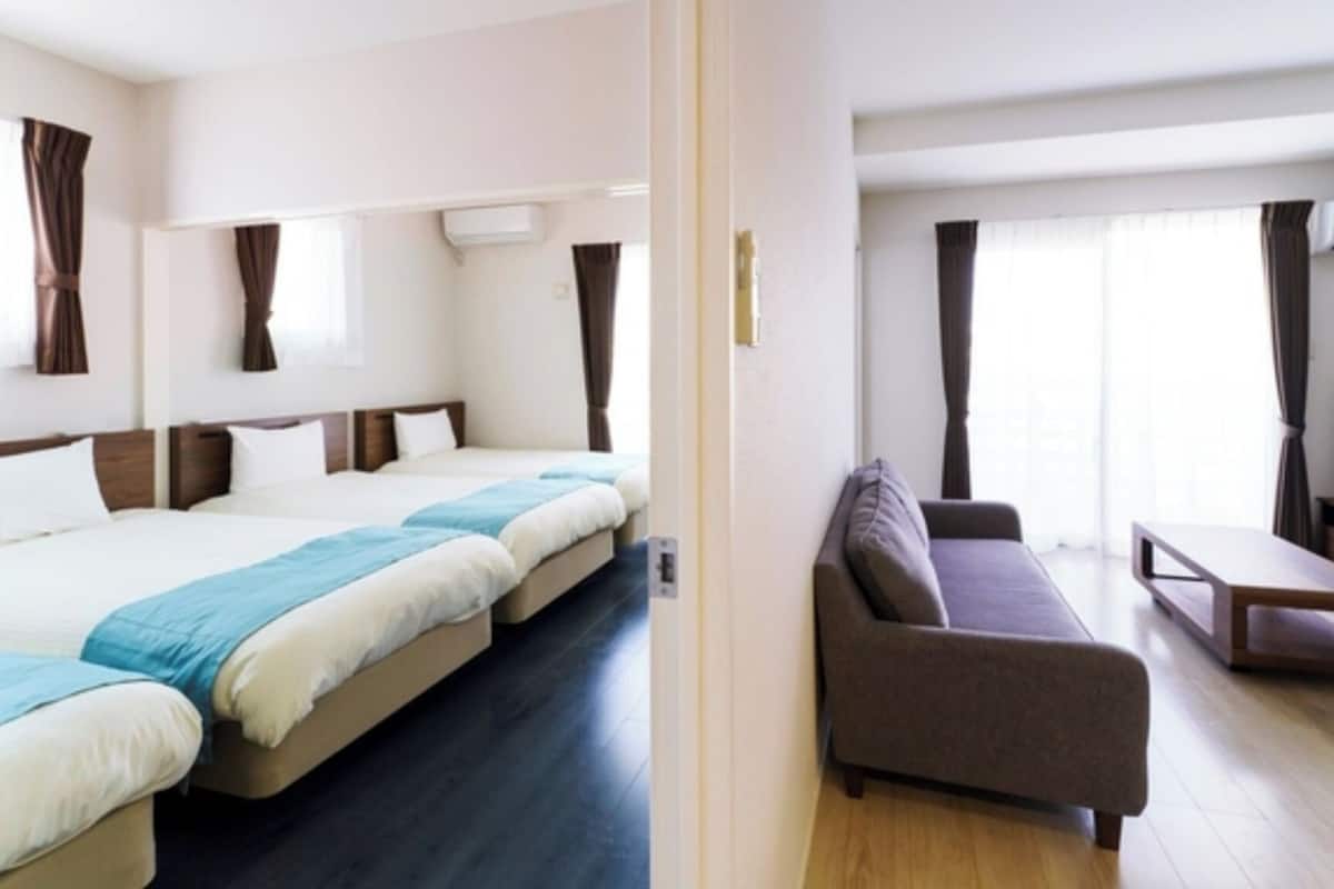 Une chambre d’hôtel avec un grand lit, un canapé, une télévision et une fenêtre avec des rideaux.