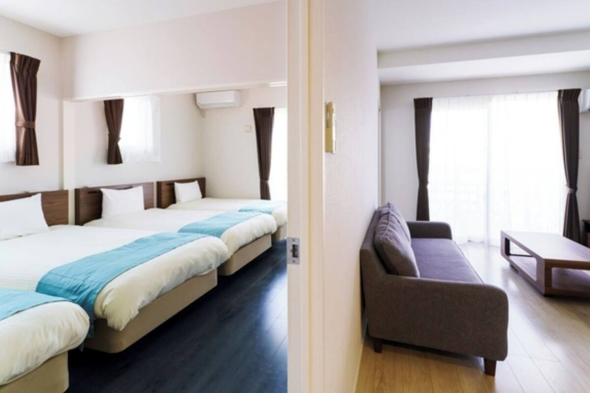 A hotel room with a large bed, a sofa, a TV, and a window with curtains.