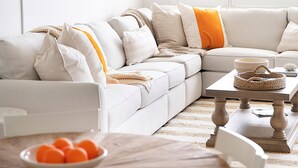 A modern living room with a sectional sofa, a round wooden table, and a large window with a view of buildings. - The Cocohut Sanibel at Loggerhead Cay 🐚 Beachfront Condo with Pool & Pickleball (Sanibel)