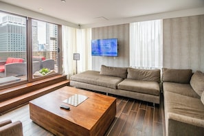 A modern living room with a sofa, a coffee table, and a TV mounted on the wall. - Manhattan | Grand Central City Base | Dining & Broadway (Manhattan)
