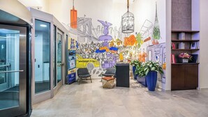 Un vestíbul modern amb un mural, zona de seients i una recepció.