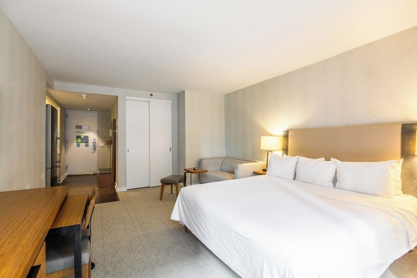 Ein Hotelzimmer mit einem Bett, einem Schreibtisch, einem Stuhl, einem kleinen Tisch und einem Sofa.