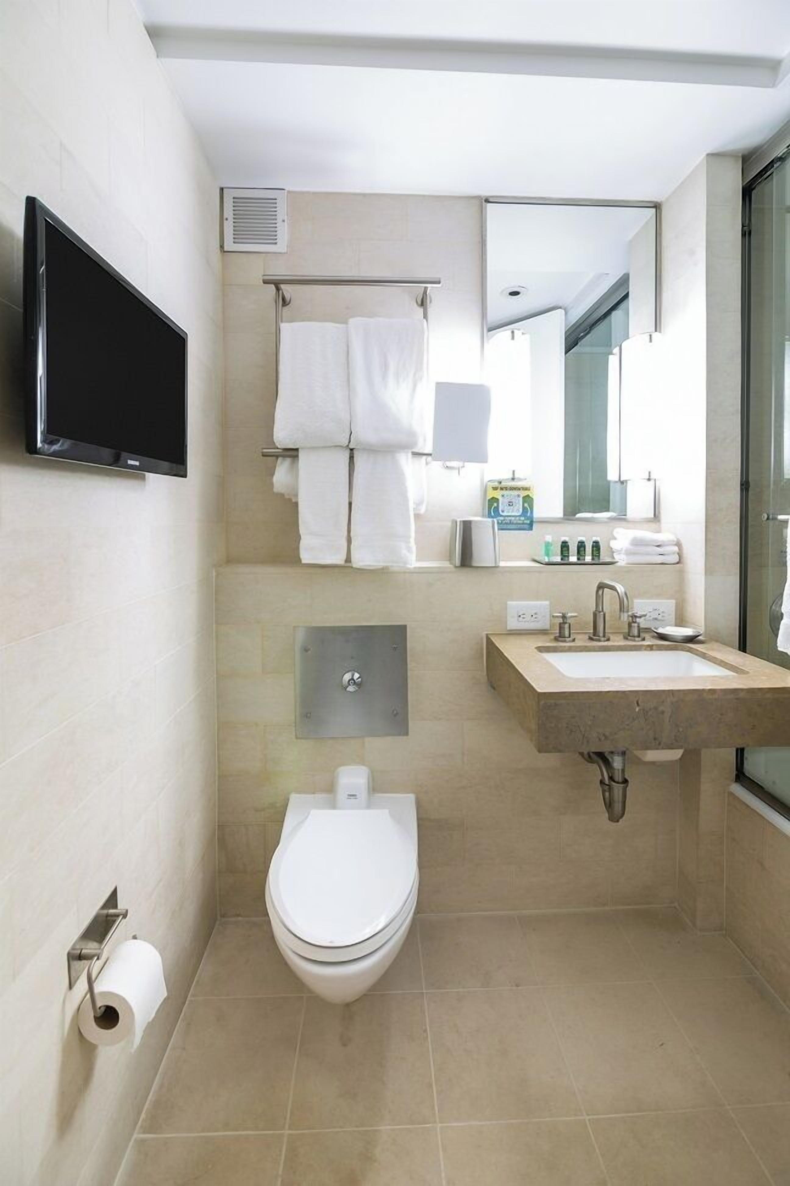 A modern bathroom with a toilet, sink, and mirror.