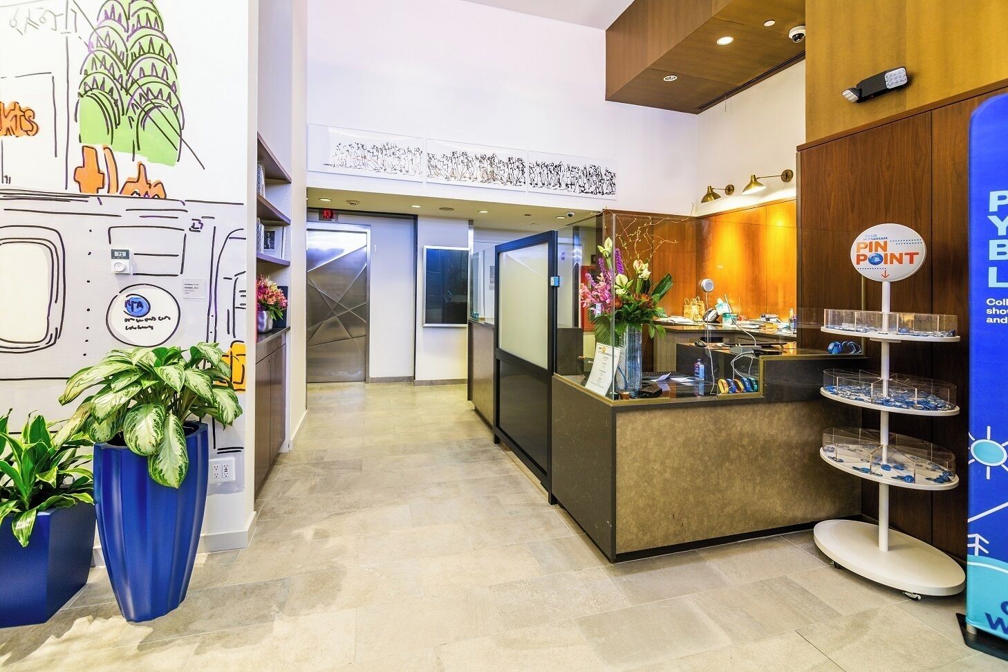 Un'area di accoglienza con un banco, piante in vaso e un cartello che indica un punto di interesse.