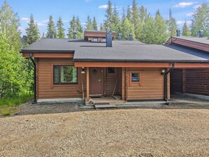 A two-story log cabin with a front porch, a garage, and a chimney.