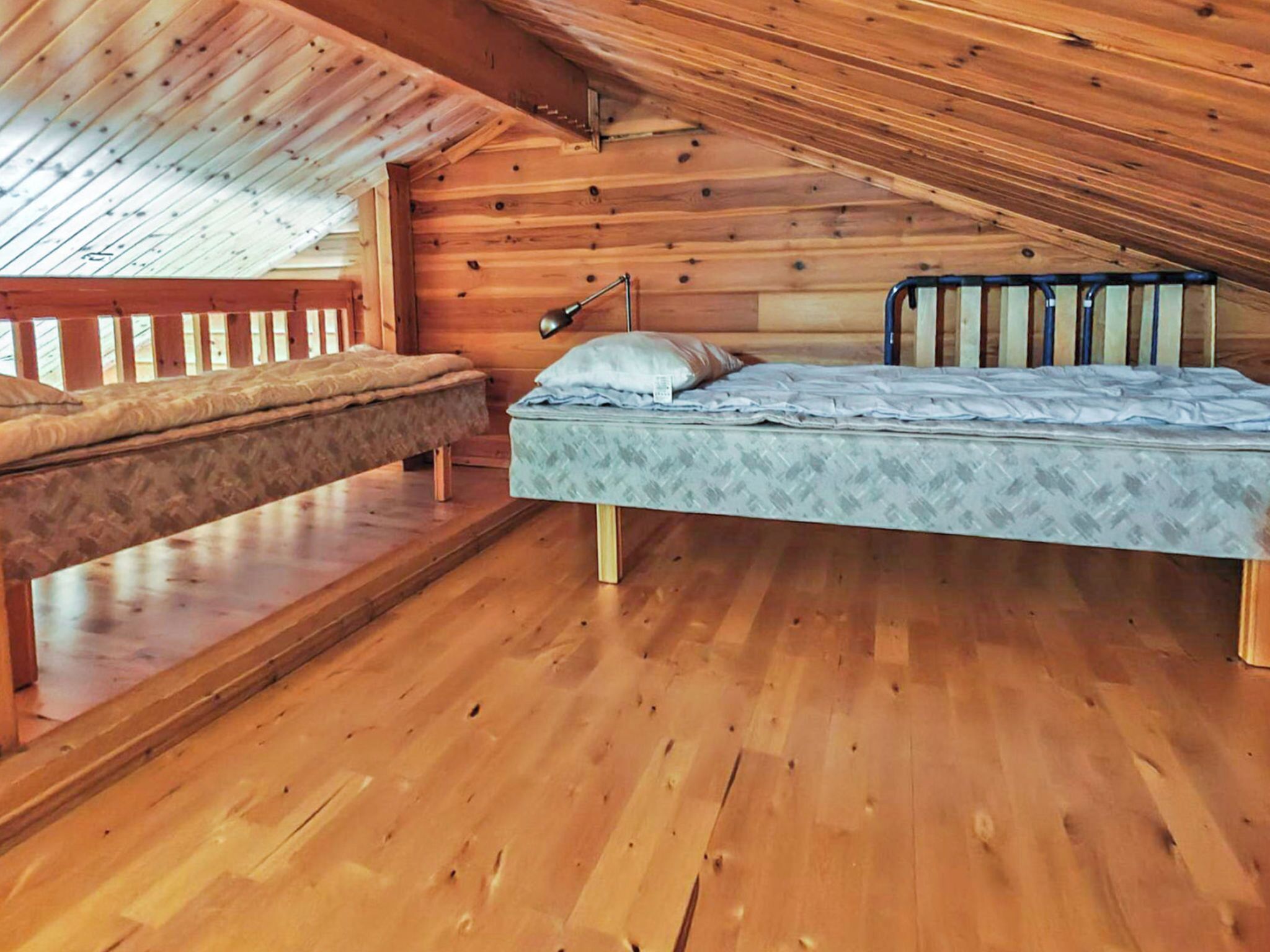 Un interior de madera con una cama, un banco y una ventana.