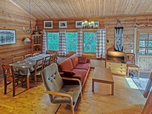 Een gezellig interieur van een chalet met een eethoek, bank en televisie.