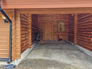 A log cabin with a wooden door, a bicycle, and a pile of firewood.