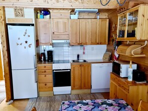 A compact kitchen with wooden cabinets, a refrigerator, a stove, a dishwasher, and a microwave.