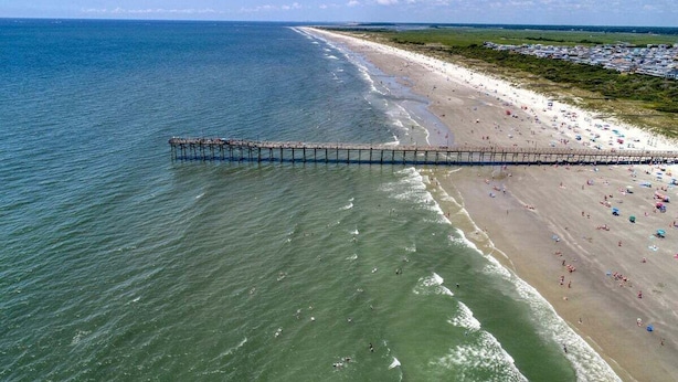 A beach with a pier extending into the ocean, sandy beach, and a line of buildings in the background. - HS-1017 Ocean View Retreat on the 10th Floor in Myrtle Beach, Sleeps 6 (Myrtle Beach)