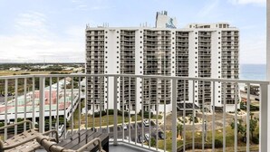 A high-rise hotel with multiple balconies, a rooftop pool, and a view of the ocean.