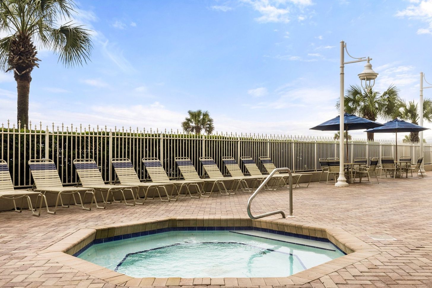 A pool area with lounge chairs, a hot tub, and a fenced poolside.