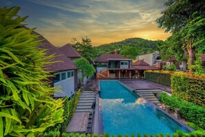 Una piscina rodeada de exuberante vegetación y casas modernas bajo un cielo despejado.