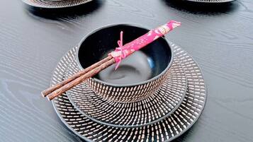 A table with three black bowls and chopsticks on a black tablecloth.