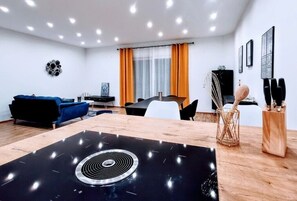 A modern living room with a black stove, blue sofa, white chairs, and a dining table.