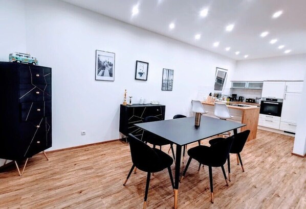 A modern kitchen with white cabinets, a black countertop, and a dining area with a black table and chairs.
