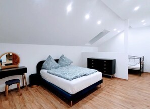 A bedroom with a bed, a desk, a chair, a wardrobe, and a bunk bed.