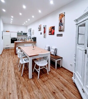 A modern kitchen with white cabinets, a wooden dining table, and a bench. - Charming Vacation Home “Marie Antoinette” with Wi-Fi, Terrace & Garden (Schwandorf)