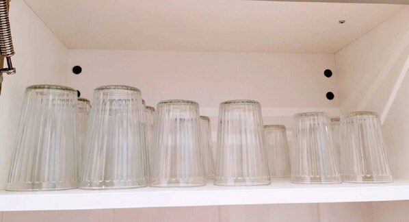 A white shelf with multiple clear glass jars.