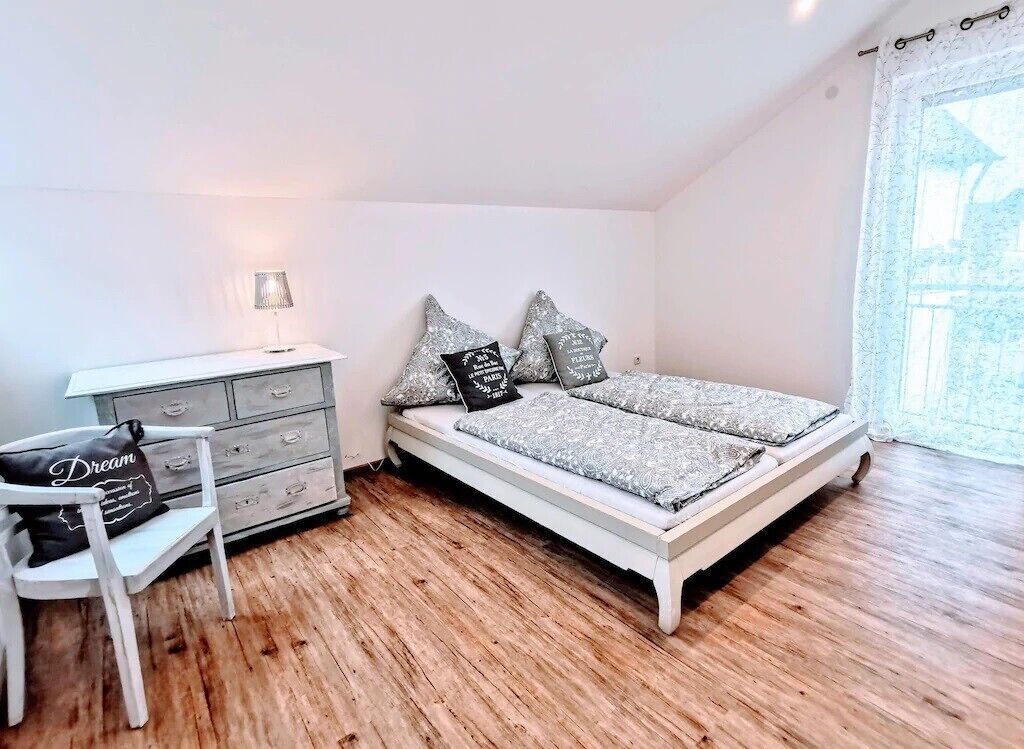 A bedroom with a bed, a dresser, a chair, and a window.