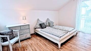 A bedroom with a bed, a dresser, a chair, and a window.