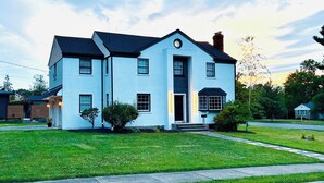 Une maison à deux  étages avec un porche à l’avant, une cheminée et une pelouse bien entretenue.
