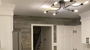 Une cuisine moderne avec des meubles blancs, un réfrigérateur encastré et un mur d’accent en bois.