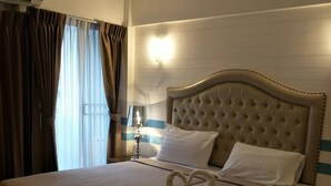 Ein Hotelzimmer mit einem großen Bett, einem Kopfteil, einer Nachttischlampe und einem Fenster mit Vorhängen.