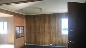 A room with wooden panel walls, a dark floor, and a door on the right. - Camping with a Roof, bathroom and Kitchen (Palm Beach)