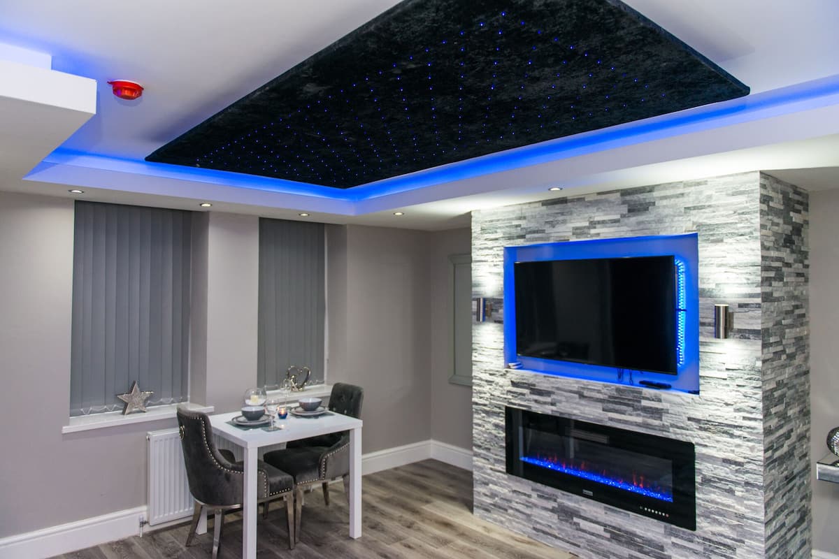 Een moderne woonkamer met een stenen openhaard, een flatscreen televisie en een plafond met een sterrenlicht ontwerp.