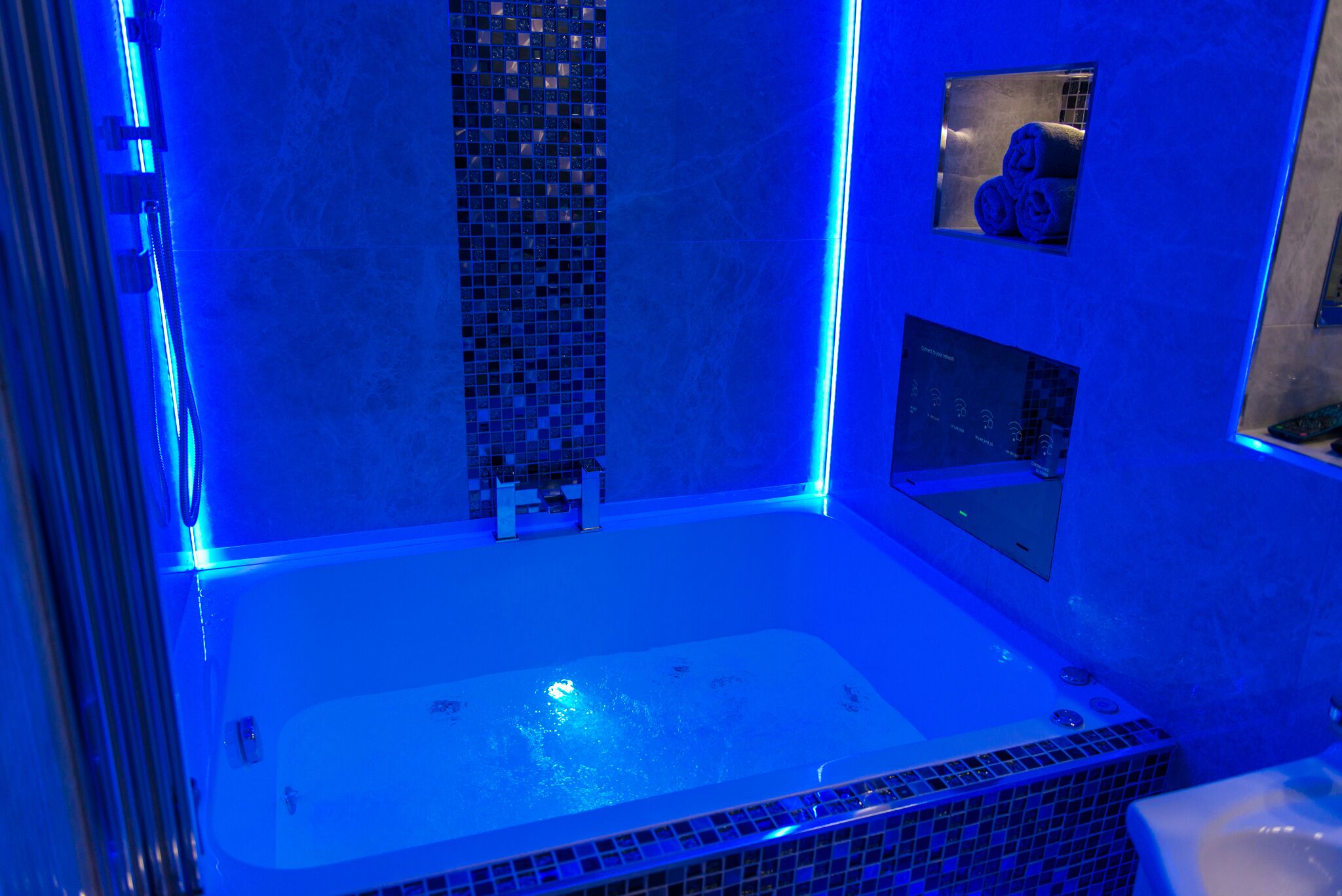 A modern bathroom with a large bathtub, a shower area, and a small window with towels.