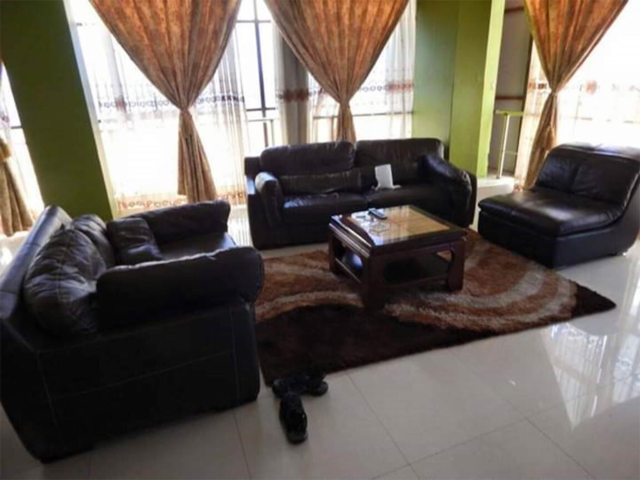 A living room with two black leather sofas, a coffee table, and a rug.