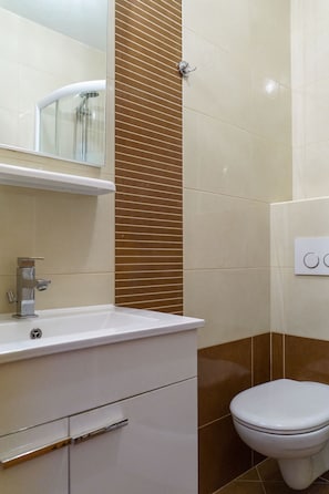 A bathroom with a white sink, a mirror, a toilet, and a wall-mounted light switch.