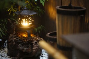 A traditional lantern on a wooden base with a rustic design, surrounded by greenery. - Yamagata Kyomachi Hatago Daitokuji (Kyoto)