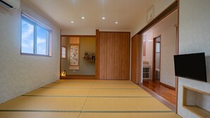 Une pièce de style japonais traditionnel, avec un sol recouvert de tatamis, une porte coulissante, un téléviseur et une fenêtre donnant sur le ciel.