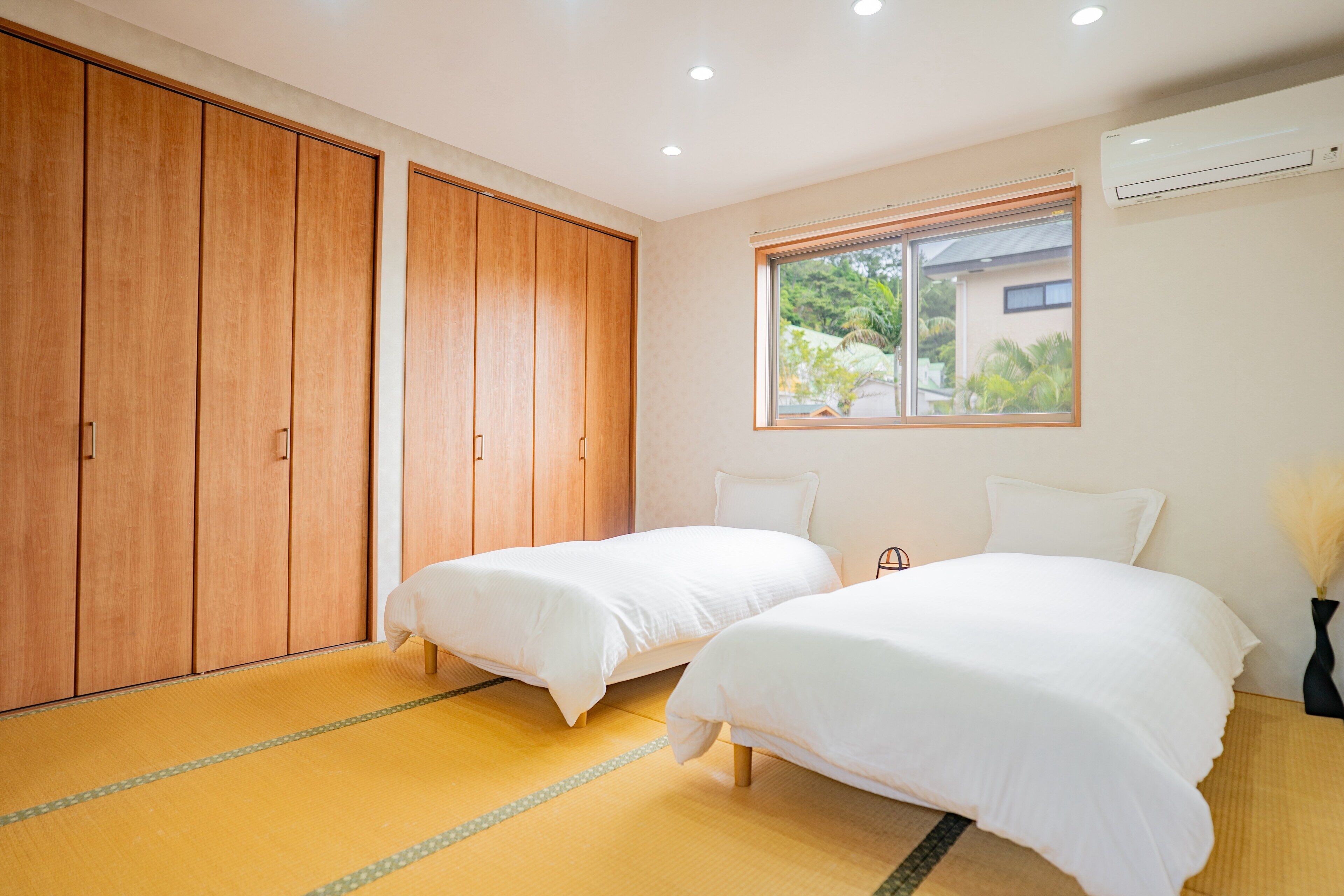 Una habitación con dos camas, un armario grande y una ventana con vistas a zonas verdes.