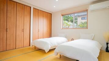 Una habitación con dos camas, un armario grande y una ventana con vistas a zonas verdes.