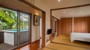 Une chambre d’hôtel avec un lit, une télévision, une porte-fenêtre coulissante donnant sur une piscine et des panneaux de bois aux murs.
