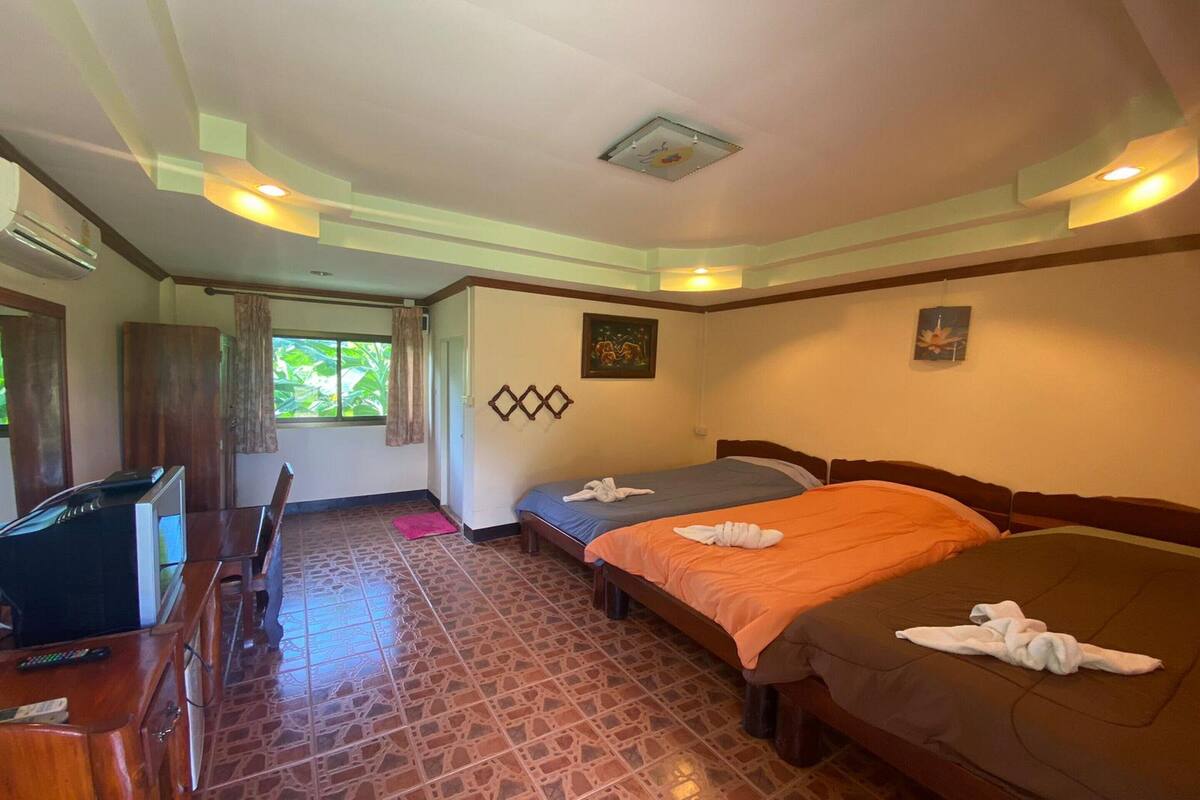 A hotel room with two beds, a desk with a TV, and a window with curtains.