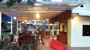 An outdoor covered patio area with wooden furniture, a red bean bag, and a bar area.