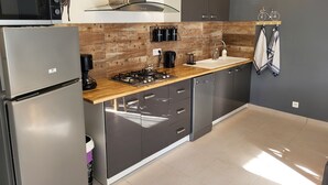 A modern kitchen with a stainless steel refrigerator, a built-in microwave, a gas stove, and a sink. - Small stone house in the heart of Périgord Noir (Salignac-Eyvigues)